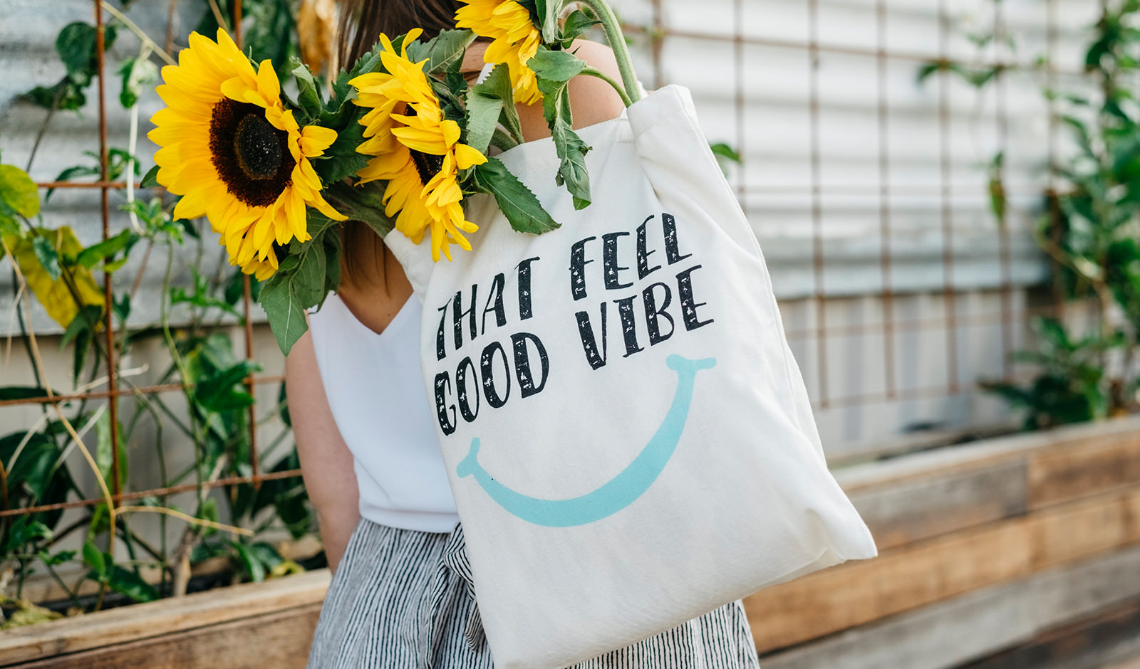 An image of a girl carrying a tote bag filled with sunflowers