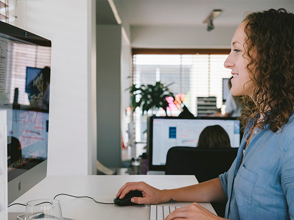 A woman smiling at her computer as she works