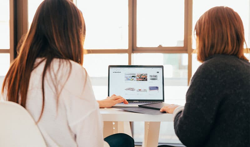Digital marketing in times of uncertainty - two women sitting at a table looking at a laptop screen