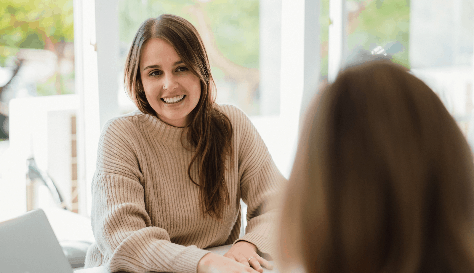 How to best communicate with your designer. Image of Lemon Tree's Creative Lead, Bianca, sitting at a table and smiling whilst talking to a client.