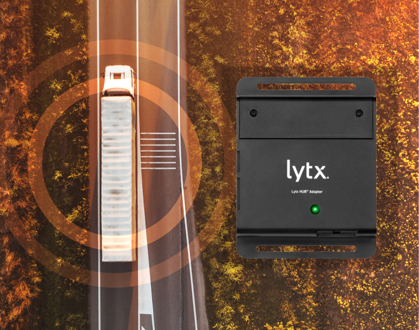 An aerial view of a white semi-truck on a road surrounded by autumn trees, with an orange circular graphic overlay and a black Lytx device with a green indicator light displayed to the right.
