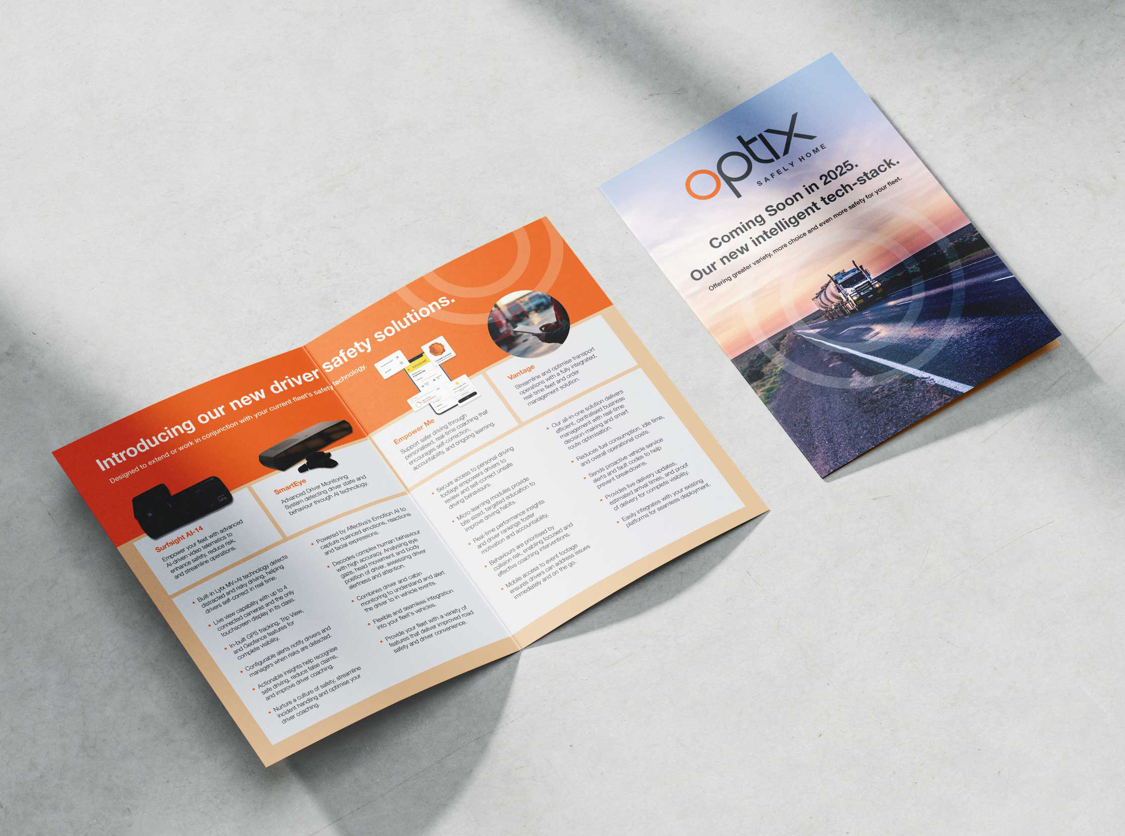 Two brochures on a light surface. One is open, showing driver safety solutions with orange accents and text. The other is closed, displaying a truck on a highway and the text “optx. Coming Soon in 2023. Our new intelligent dashcam.”.